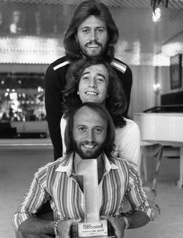 Cei trei frați Bee Gees — Barry, Robin și Maurice Gibb — într-o fotografie promoțională din 1977.