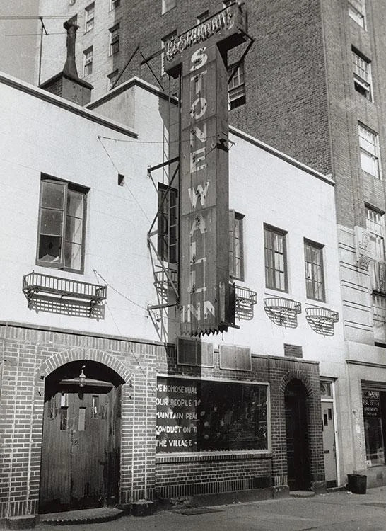 Fațada Stonewall Inn în 1969, cu semnul vertical al clubului și mesajul din vitrină.